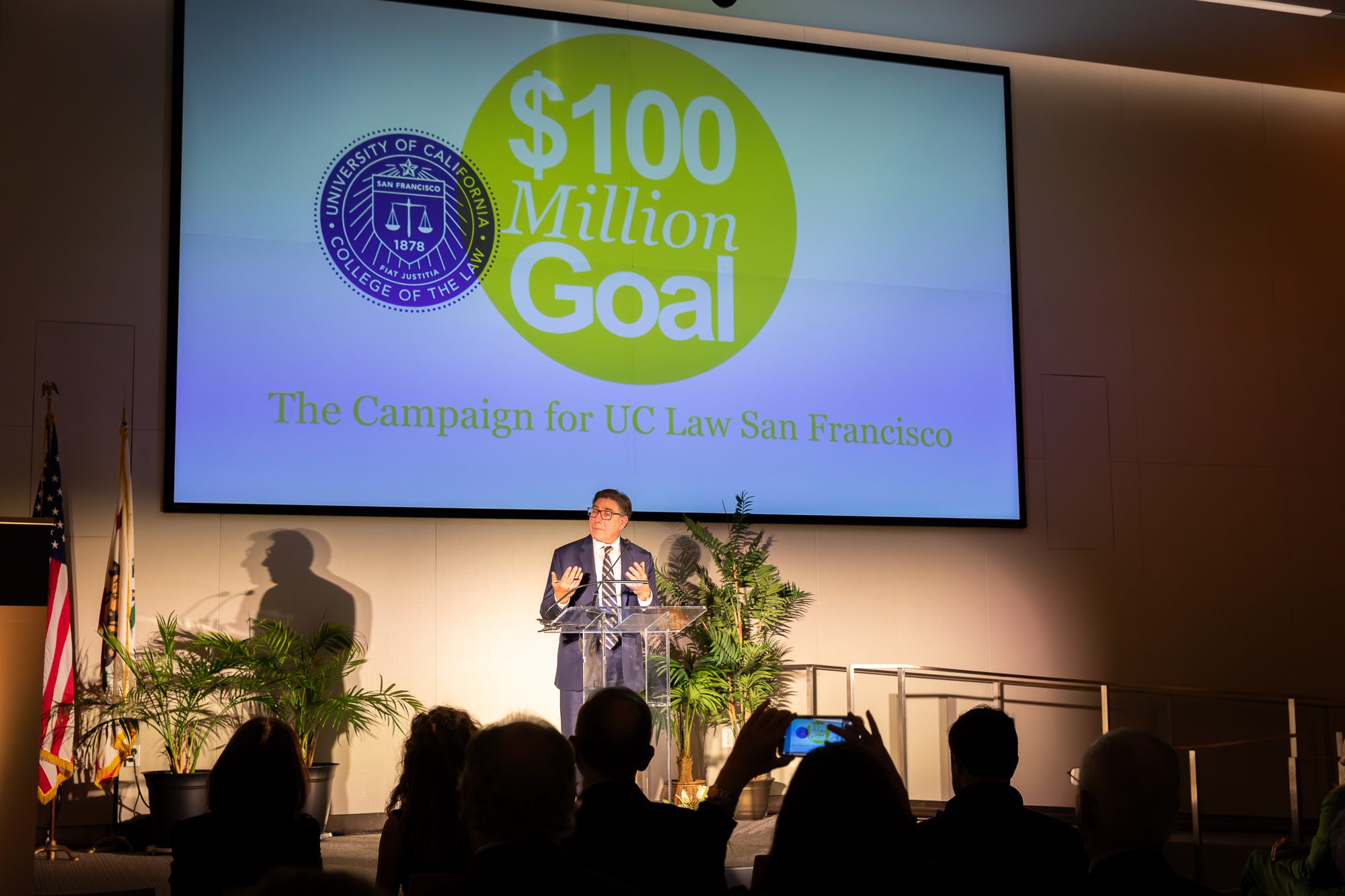 Chancellor and Dean David Faigman announces the $100 million campaign goal in an auditorium with a sign listing the goal.