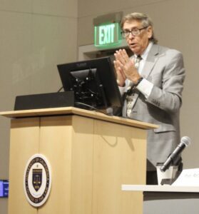 Rory Little speaks behind a podium