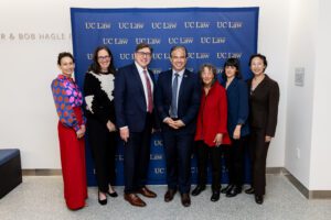 A group of five women and two men stand in front of a navy blue "UC Law SF"-branded backdrop.