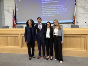Leonda Kruger poses with three law students in a mock courtroom.