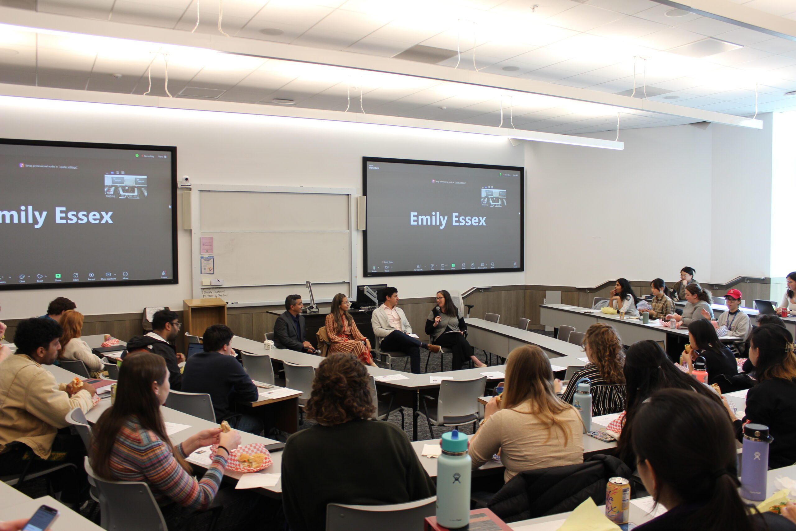 A panel with four people sits in front of a classroom full of students