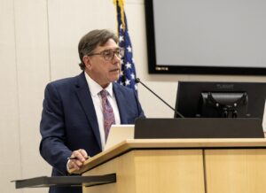 David Faigman speaks into a microphone while standing behind a lectern.
