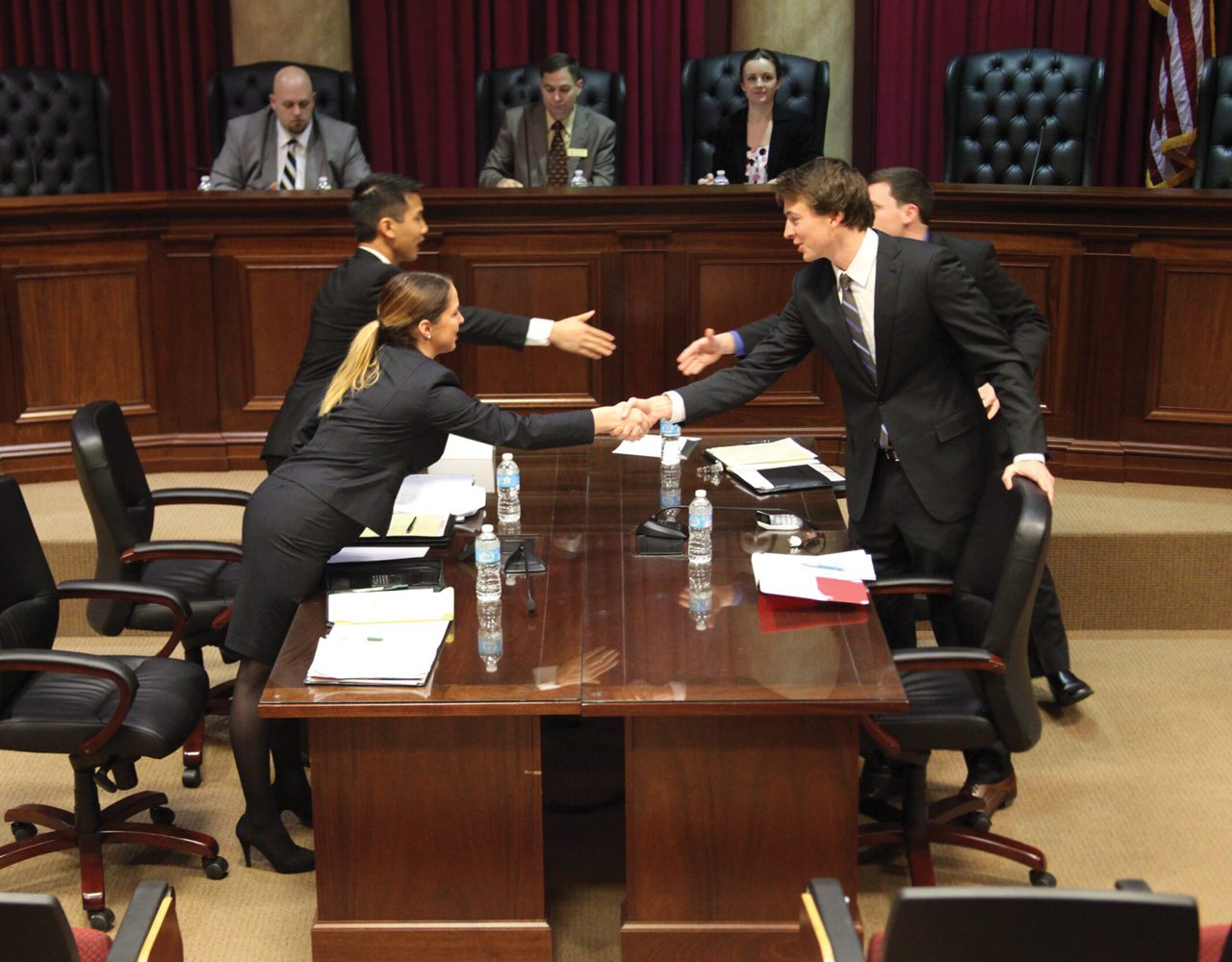 Students shaking hands across the table after a competition