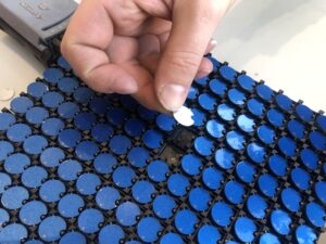 A hand holds a silver dot over a panel of two-sided blue dots.