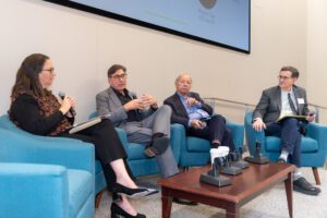 Four legal scholars sit in blue chairs during a panel discussion.