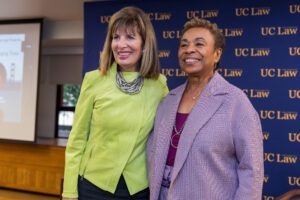 Barbara Lee smiling and standing in front of a UC Law SF backdrop at an event.