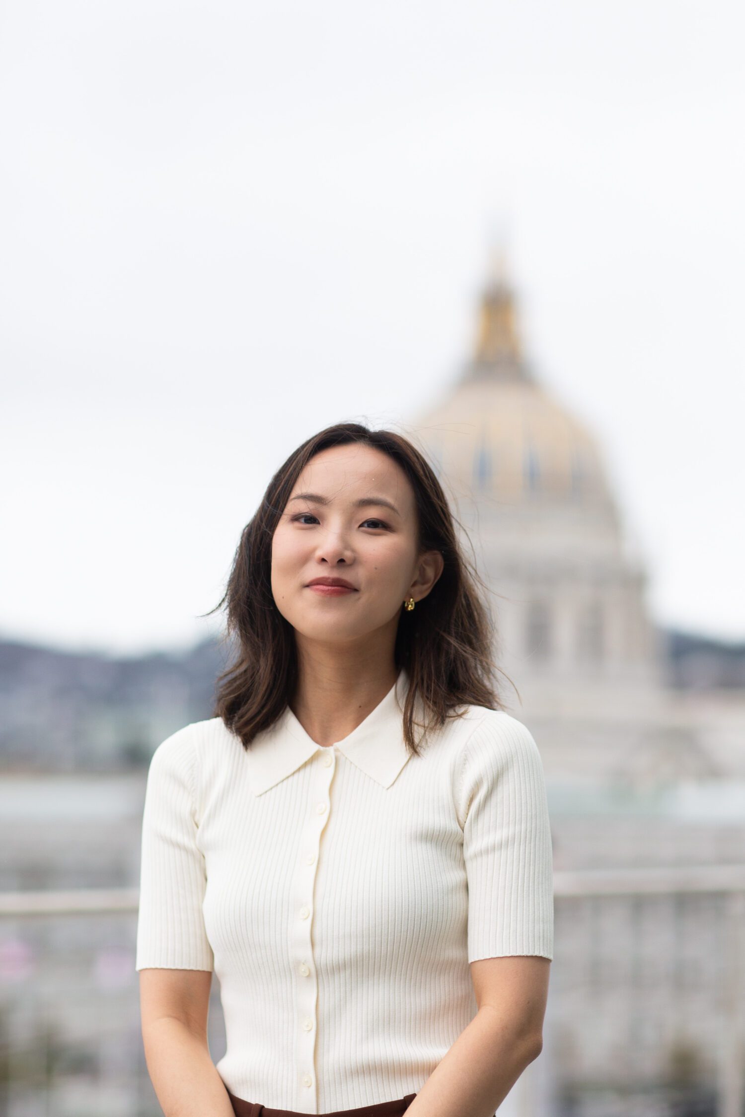 Headshot of law student Yingting Xu wearing a white shirt with the San Francisco City Hall building blurred out.
