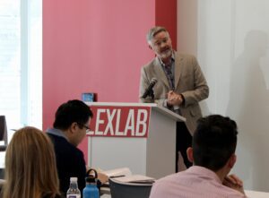 Drew Amerson speaks behind a podium at the front of a classroom.