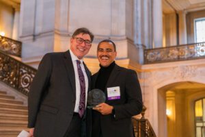 David Faigman and Myell Mergaert '20 smiling with his Alum of the Year award