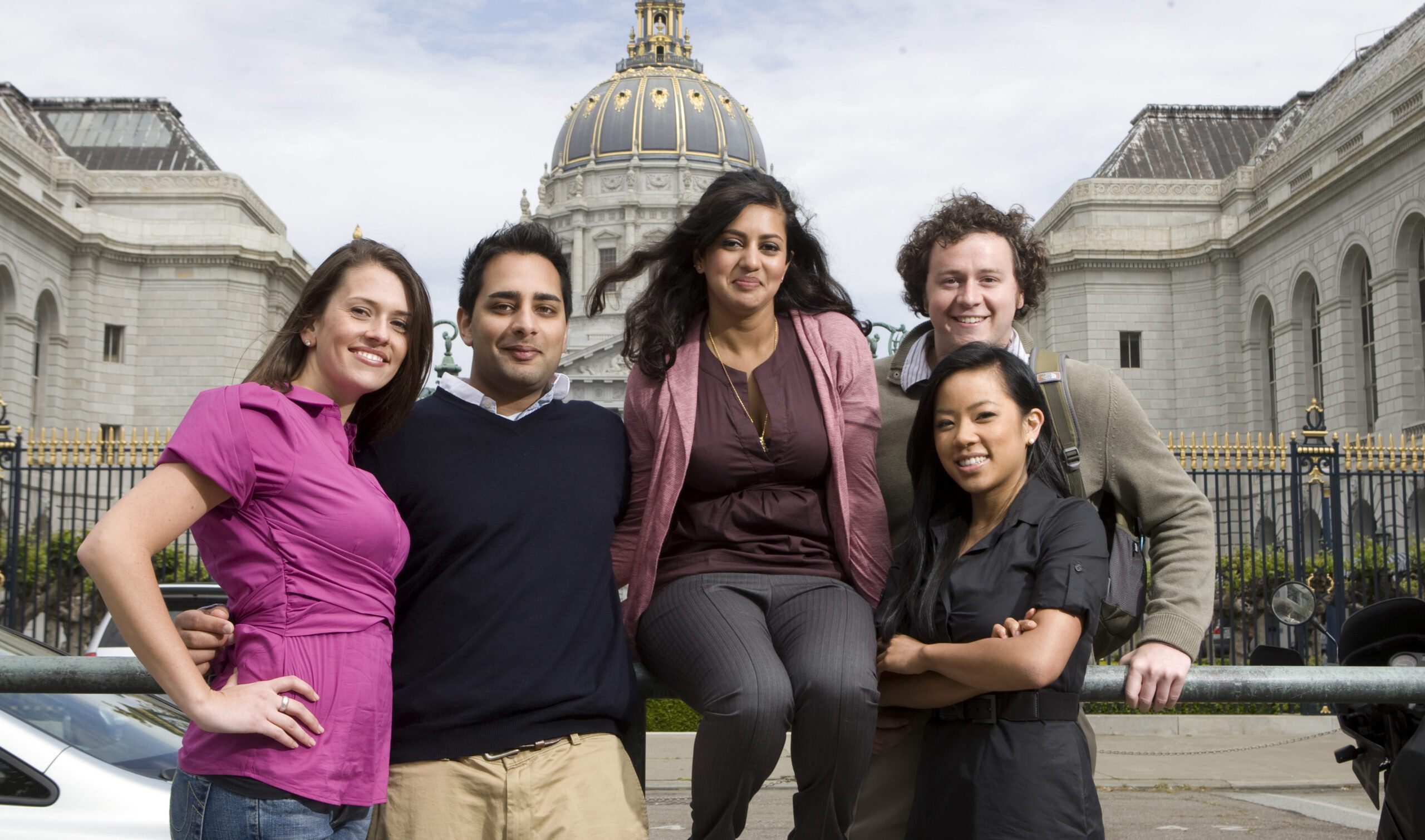 A group of smiling students. City Hall's dome can be seen in the background