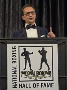 Farzard Tabatabai speaks from behind a podium at a boxing hall of fame ceremony.