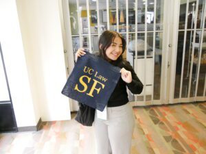 A student poses with a UC Law SF branded tote bag