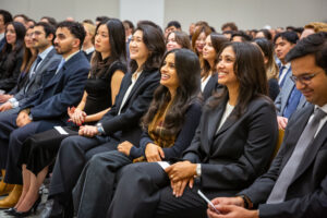 UC Law SF graduates smiling and sitting in the 198 McAllister auditorium during the swearing in ceremony