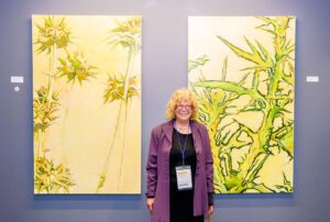 Lorrie Fink poses while standing between her two artworks.