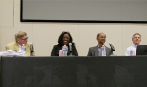 Three professors and a judge sit behind a desk during a panel talk.